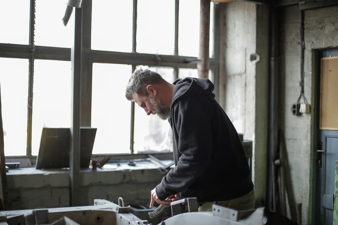 A mechanic concentrating on equipment inspection in a naturally lit workshop.